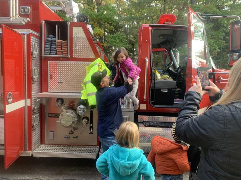 Boothbay firefighter David Steinmetz assists a pre-kindergartener off a truck during a fire safety demonstration Oct. 11 at BRES. BILL PEARSON/Boothbay Register