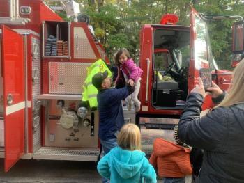 Boothbay firefighter David Steinmetz assists a pre-kindergartener off a truck during a fire safety demonstration Oct. 11 at BRES. BILL PEARSON/Boothbay Register